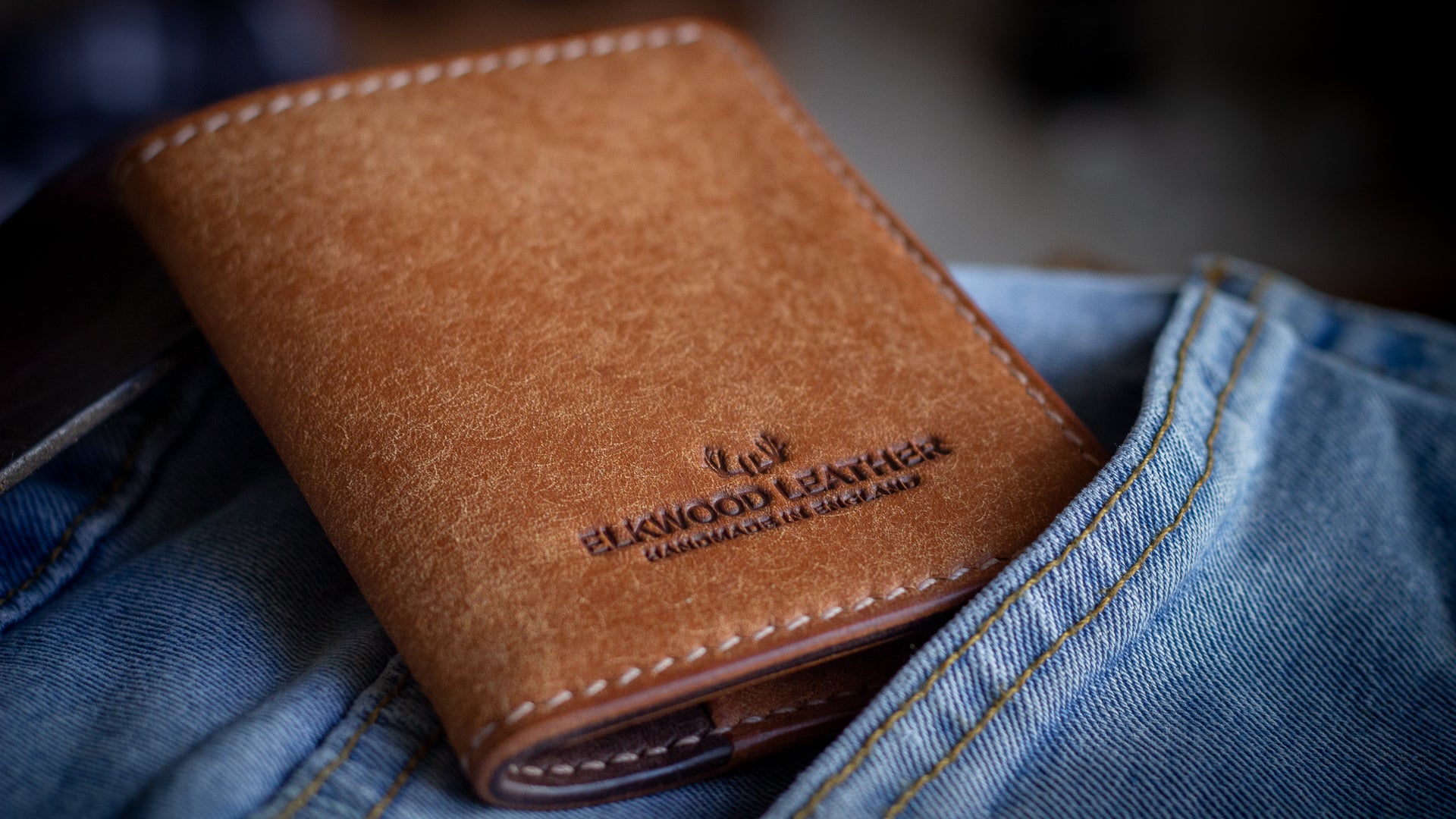 Elkwood leather brown bifold wallet closed coming out of blue jean pocket