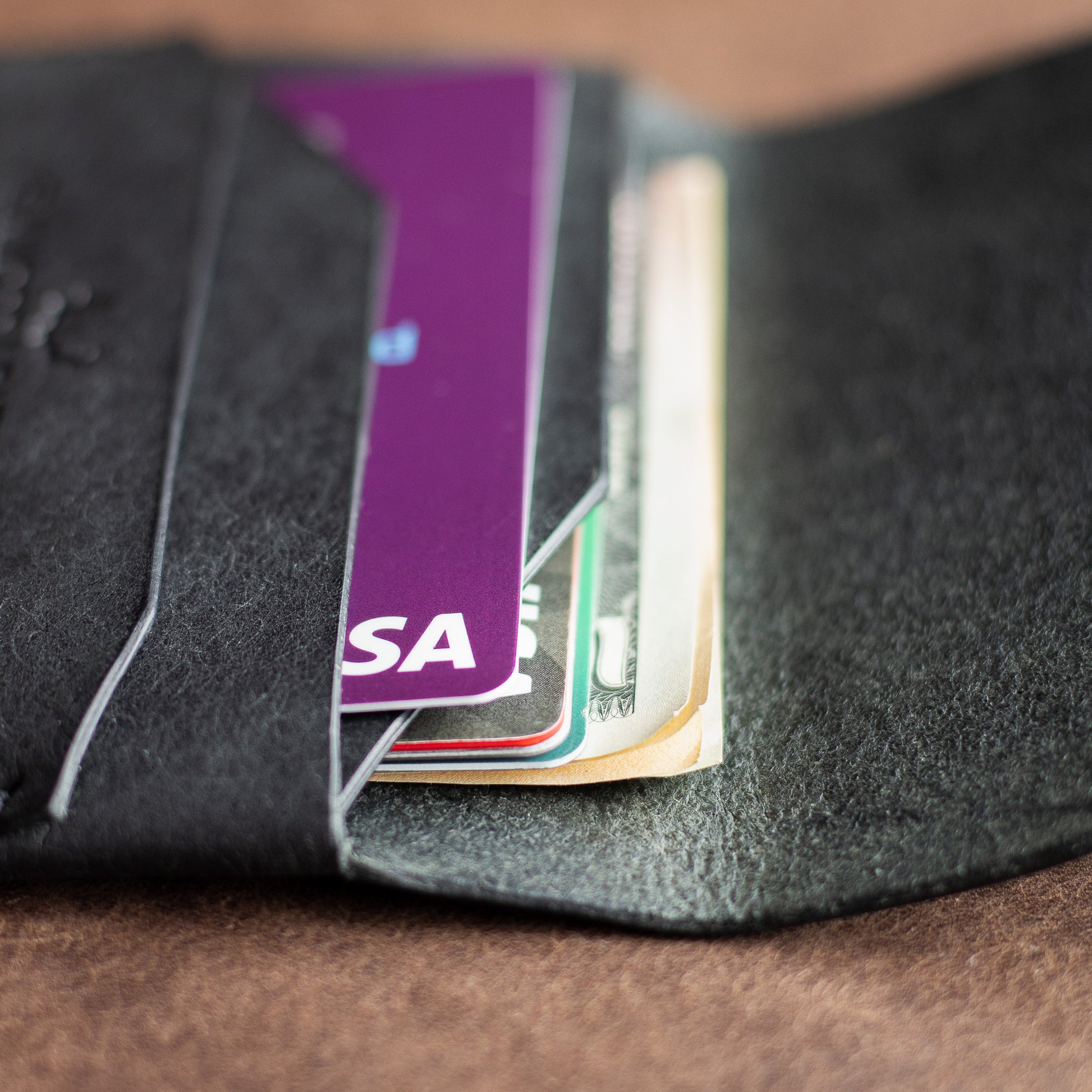 Closeup of credit cards and cash inside a black full grain leather EDC wallet