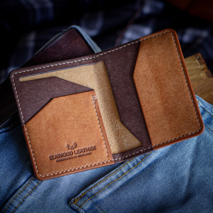 The cred brown bifold handmade leather wallet open on top of blue jean pocket