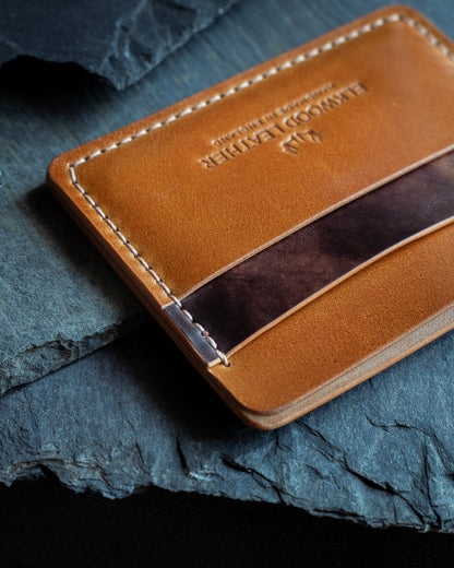 Shell cordovan leather cardholder wallet onto of slate, crafted from Rocado Whiskey & Brown Museum Leather close up saddlestitching