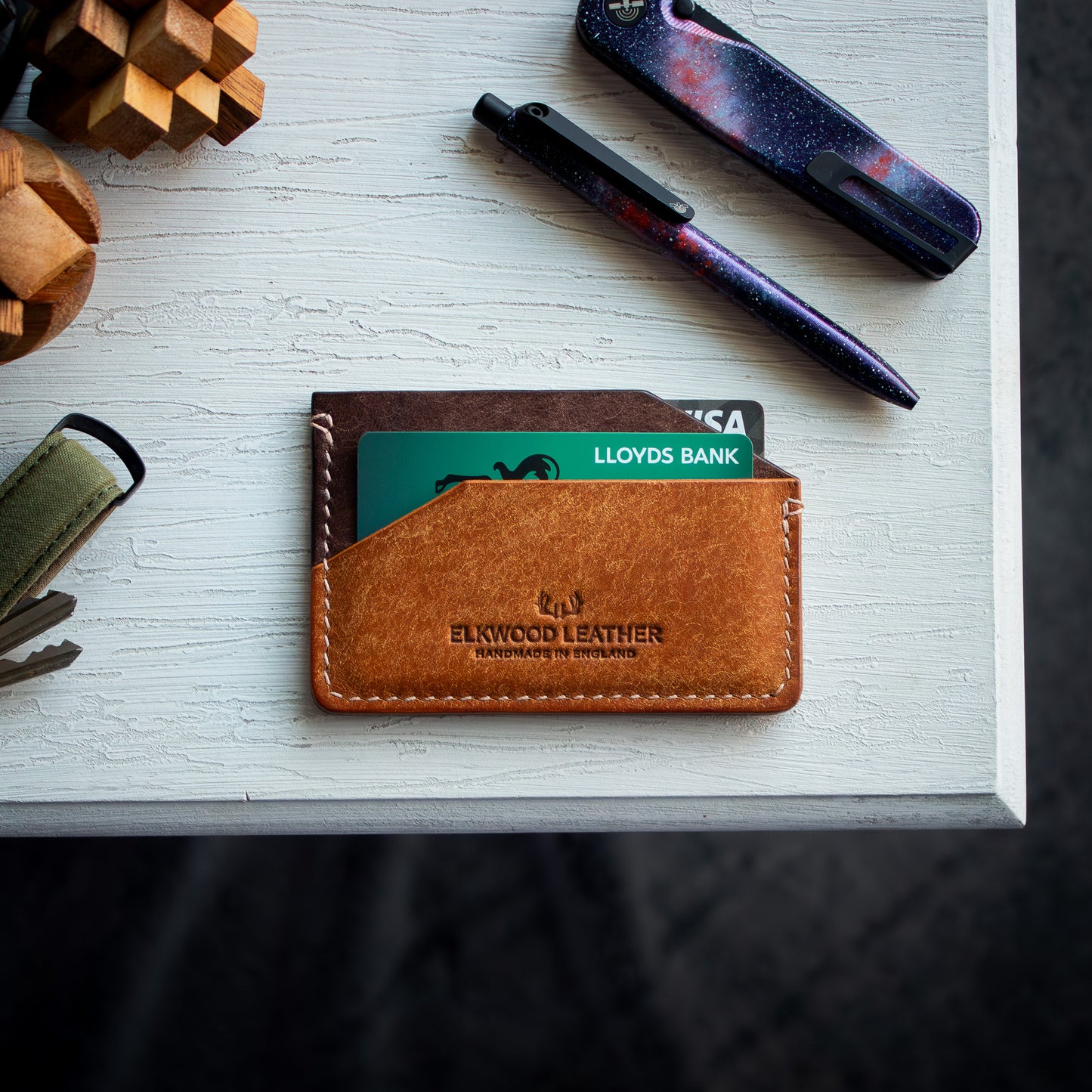 Elkwood Leather - The Aspen - minimalist full grain Italian Pueblo leather cardholder wallet with credit cards on white wooden table next to galaxy pen and knife and keys