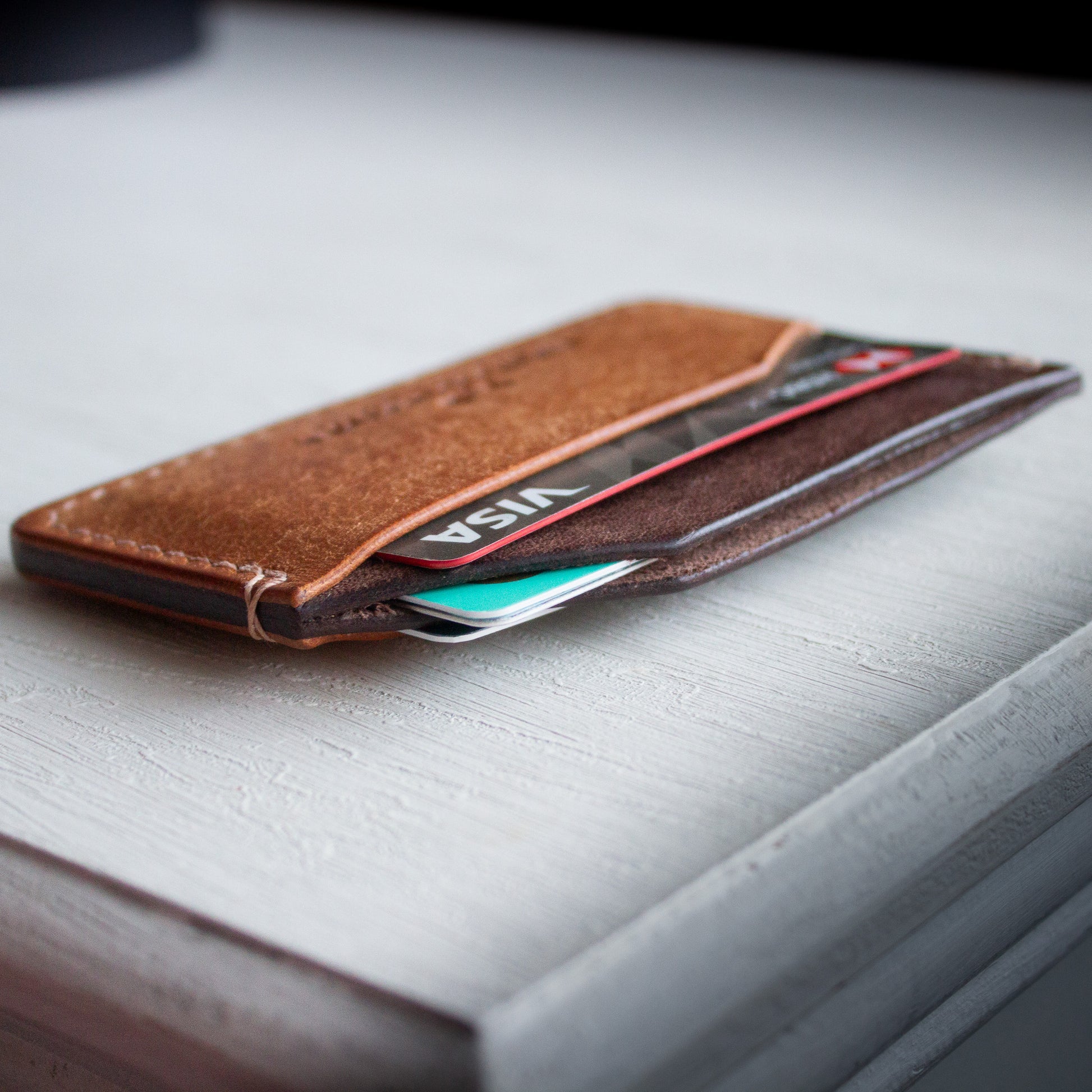 Elkwood Leather - The Aspen - minimalist full grain Italian Pueblo leather cardholder wallet on white wooden table next to galaxy pen and knife and keys close up of credit cards
