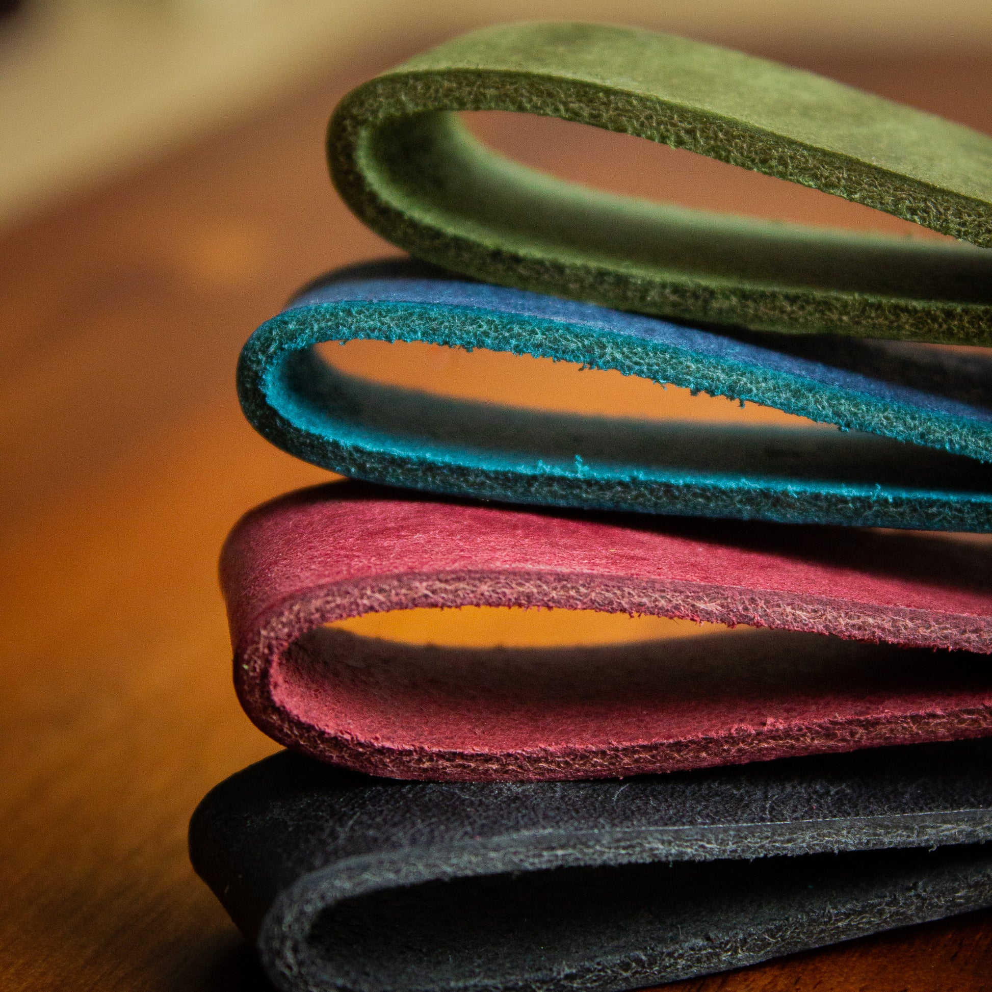 handmade leather keytags with solid brass keyring and rivet on top of wooden chopping board - Made from Peublo leather - blue, black, green, red - key loops