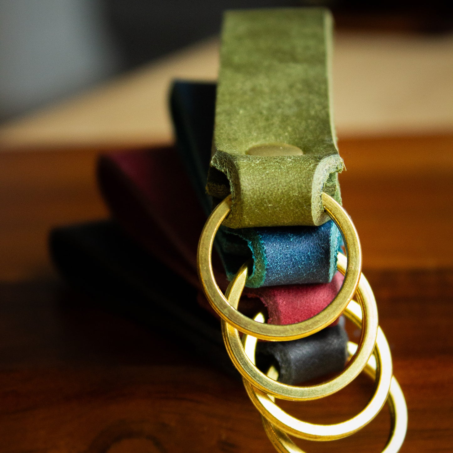 handmade leather keytags with solid brass keyring and rivet on top of wooden chopping board - Made from Peublo leather - blue, black, green, red - close up split rings