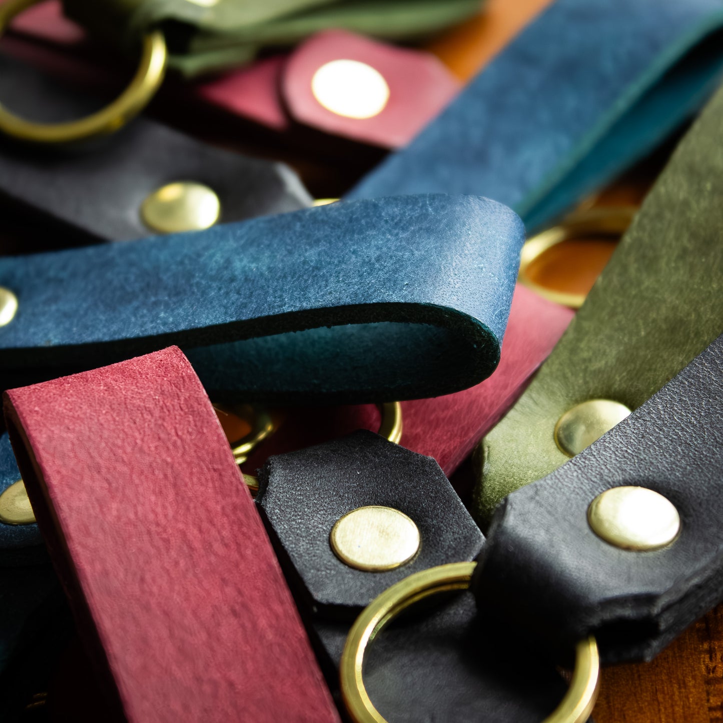 handmade leather keytags with solid brass keyring and rivet on top of wooden chopping board - Made from Peublo leather - blue, black, green, red 