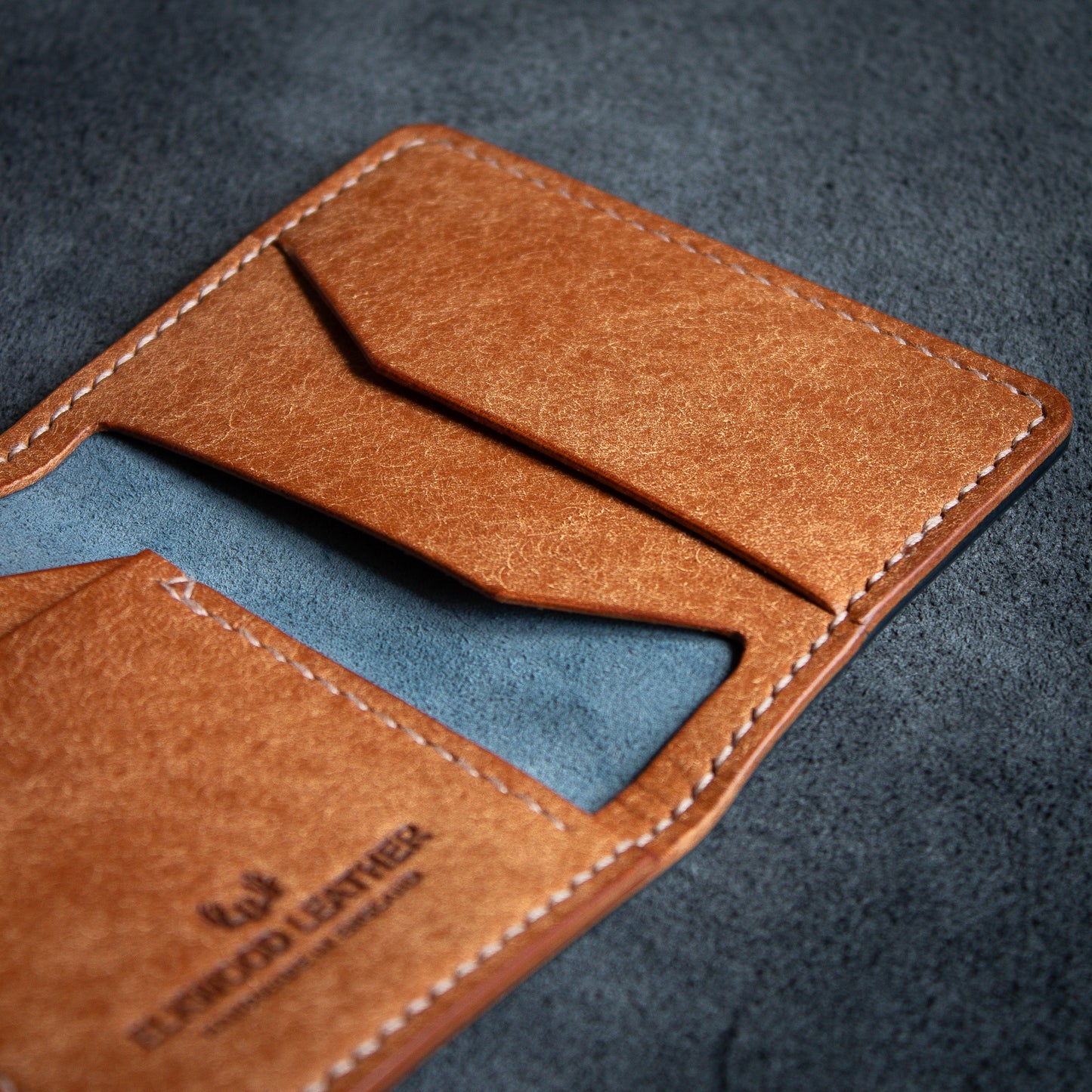 Elkwood Leather the cedar bifold wallet in Navy & Cognac Pueblo leather, on top of flesh side Nero leather hide close up pockets