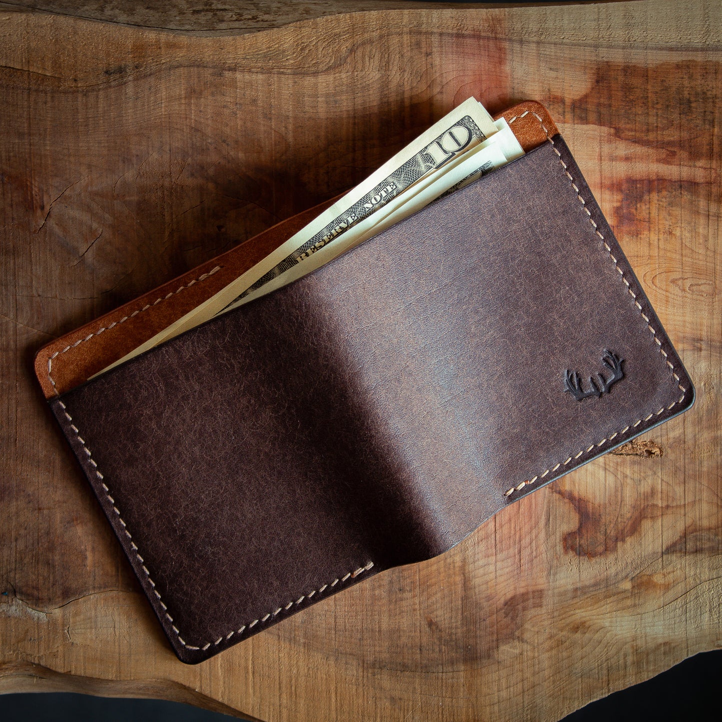 Brown leather bifold wallet with US dollar bills in cash flap