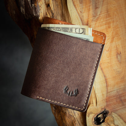 Brown leather bifold wallet closed with US dollar bills in cash flap