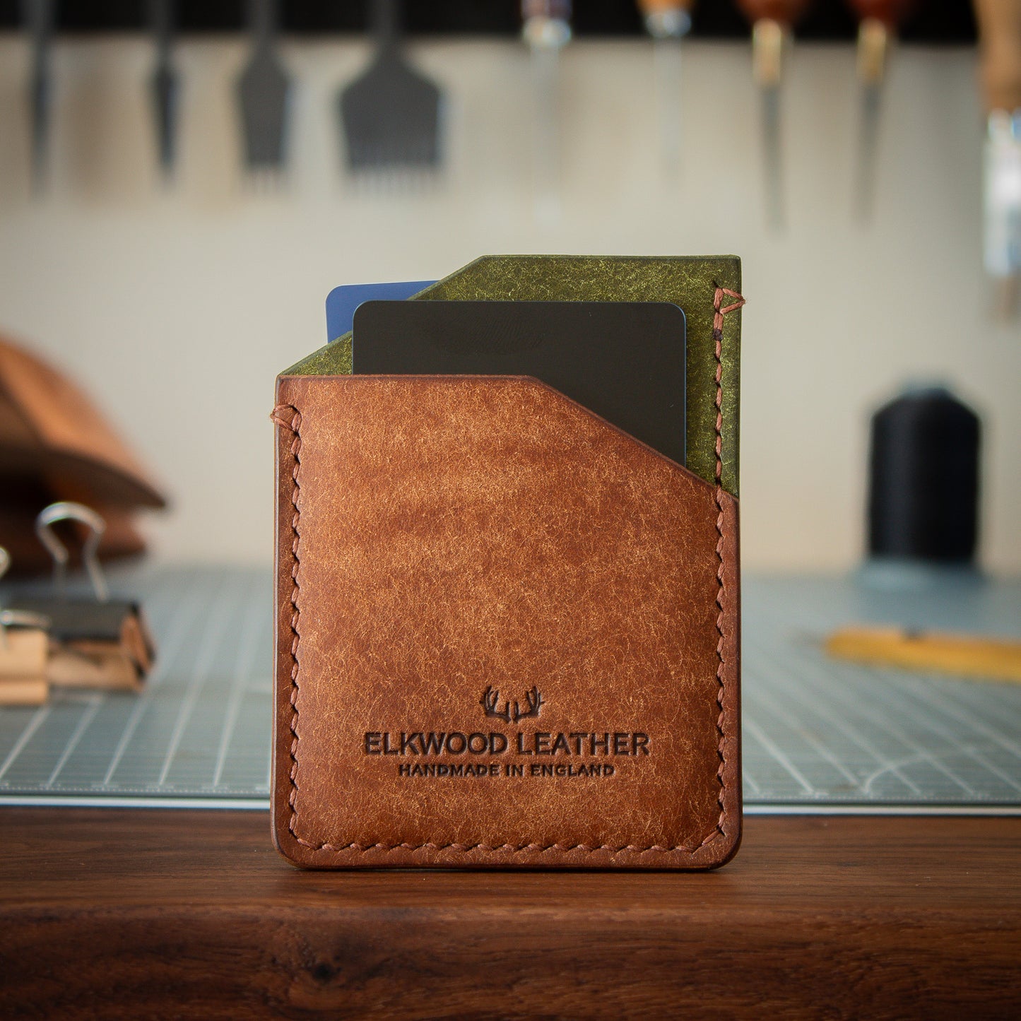 Green and Brown leather cardholder wallet on walnut table