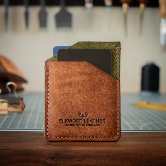 Green and Brown leather cardholder wallet on walnut table