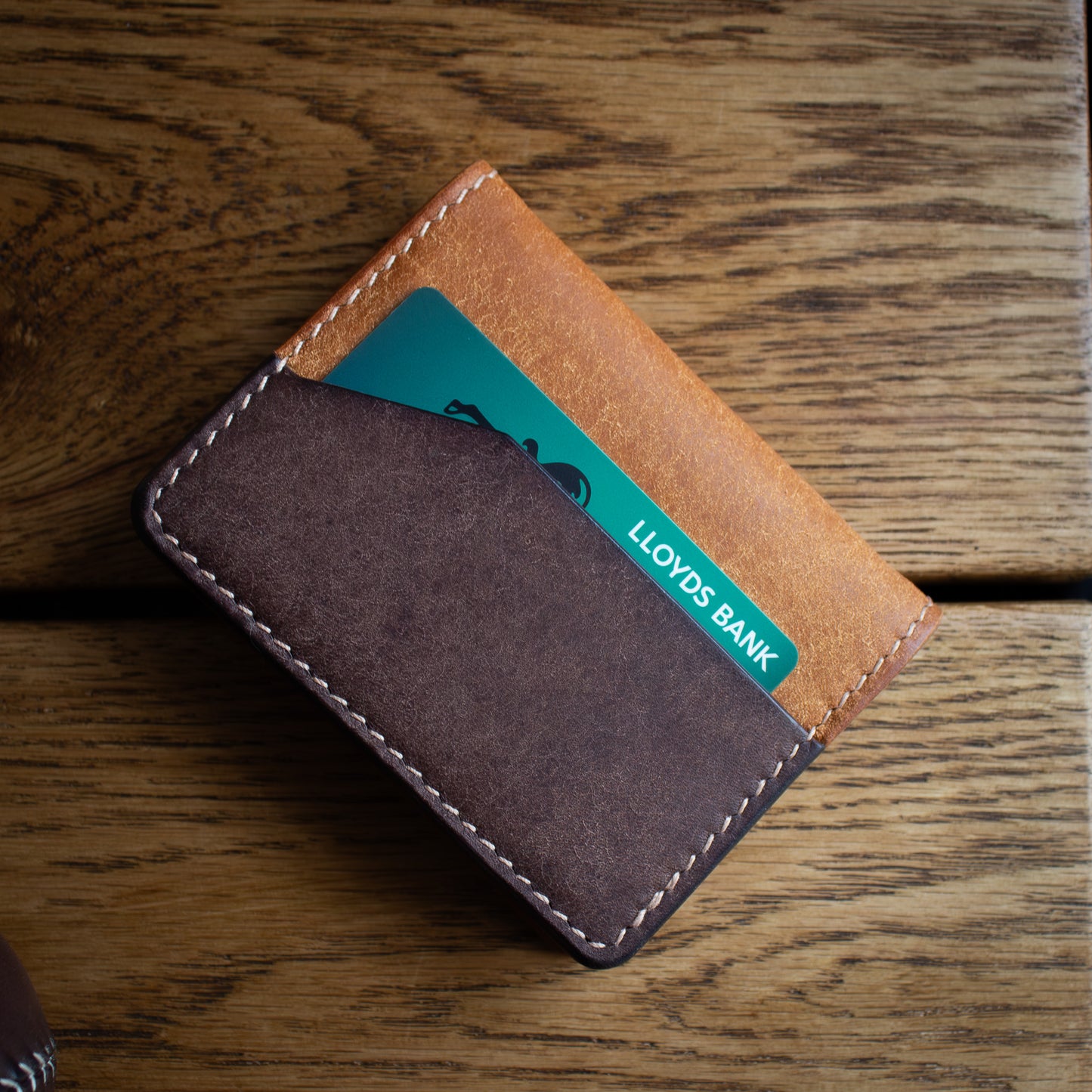 handmade leather wallet "the Cedar" ontop of wooden table. Made from Italian Pueblo leather Costagno & Cognac colors