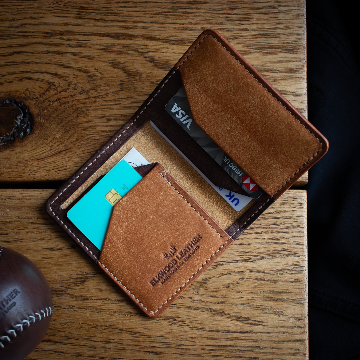 handmade leather wallet "the Cedar" ontop of wooden table. Made from Italian Pueblo leather Costagno & Cognac colors