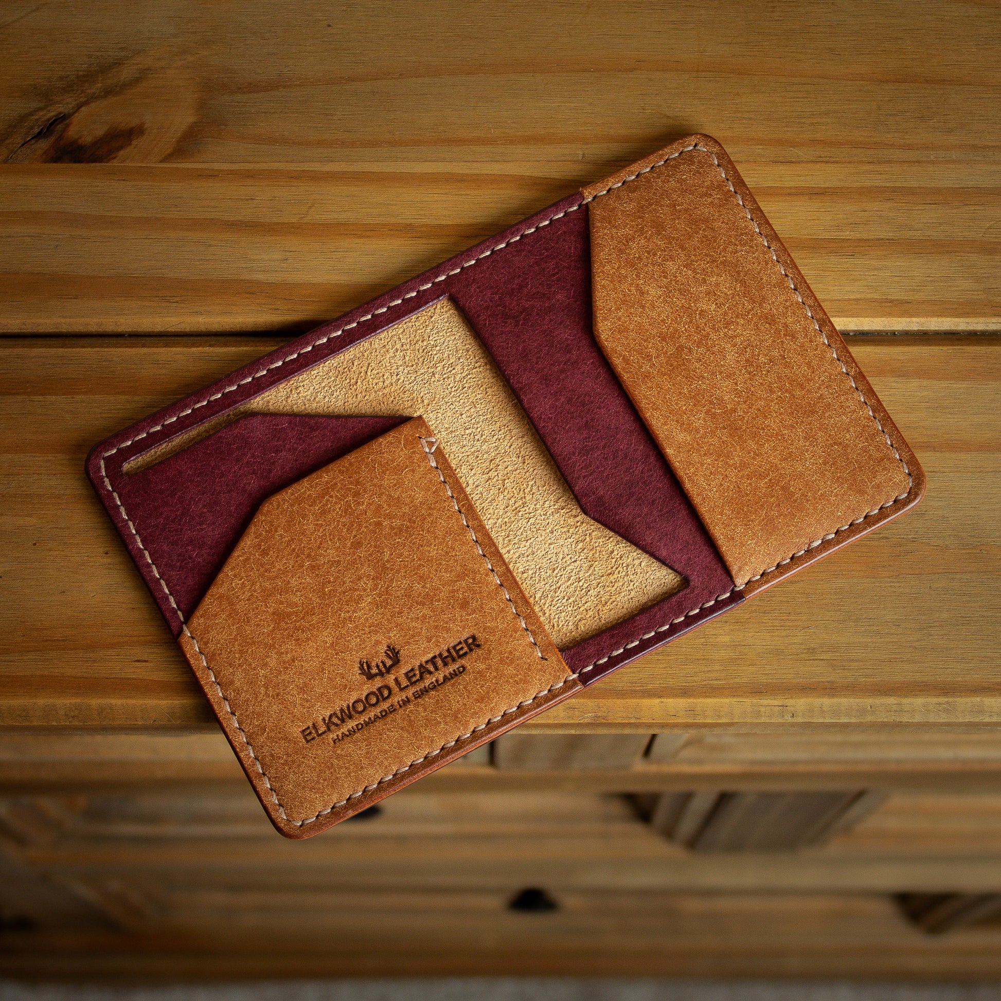 Brown and red "The Cedar" leather wallet open on wooded sideboard