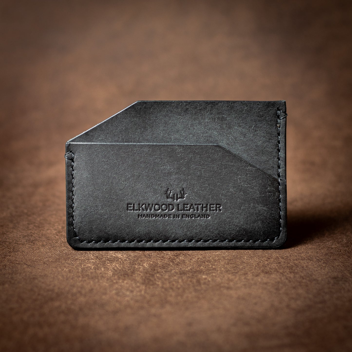 Elkwood Leather black leather cardholder wallet with black stitching on a brown leather background