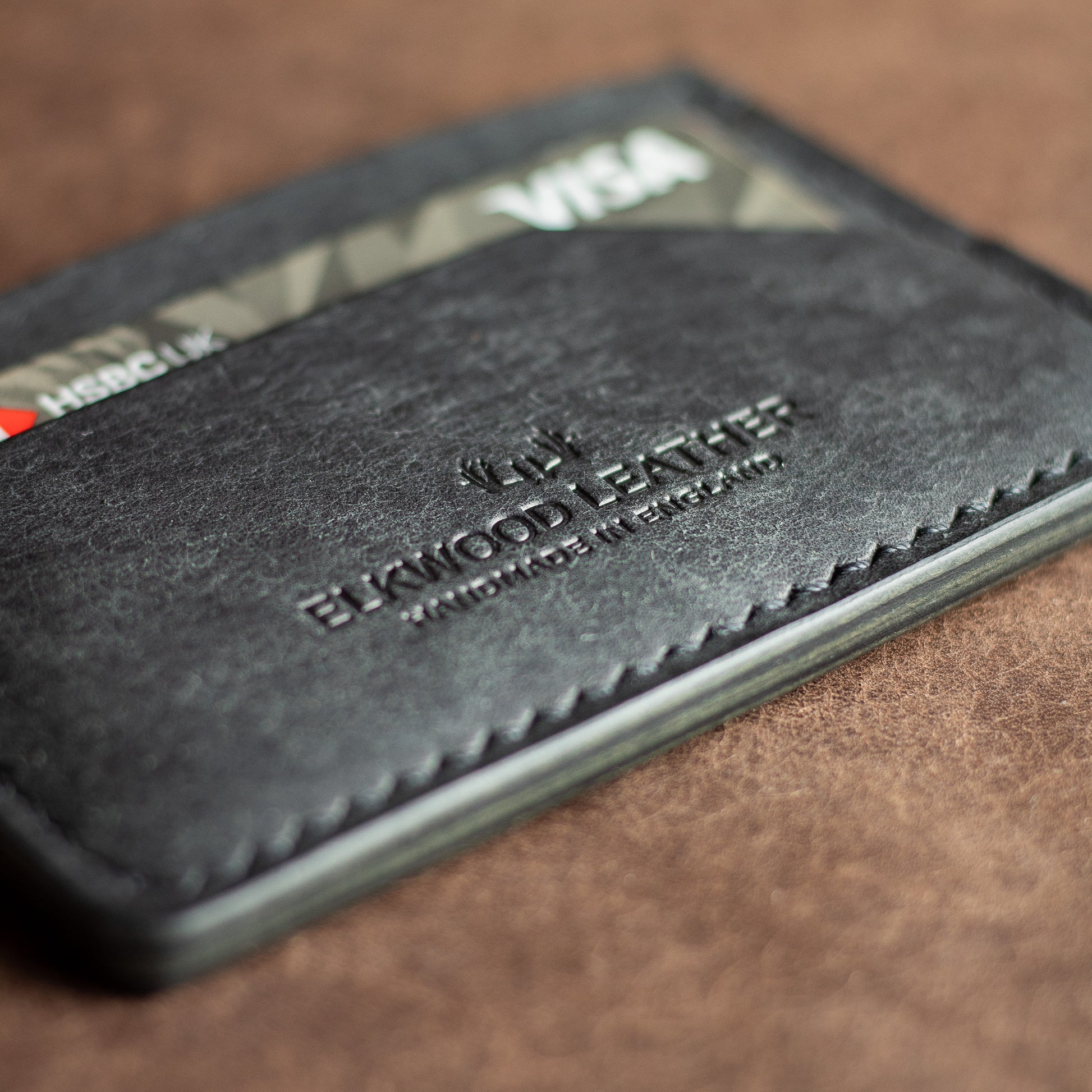 Black leather cardholder with shiny mirror edges reflecting in the light