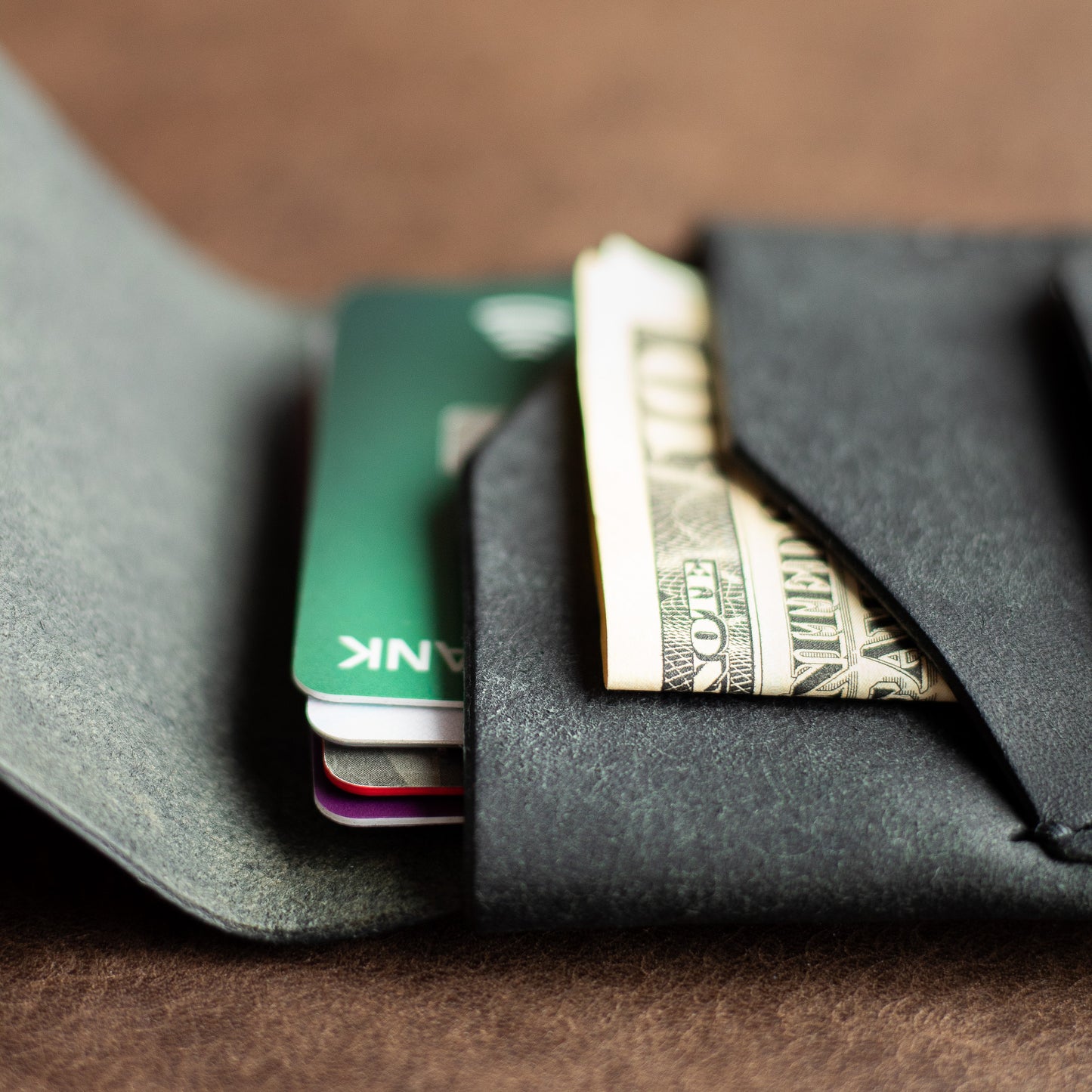 Close up of credit cards and US bills inside a black leather wallet