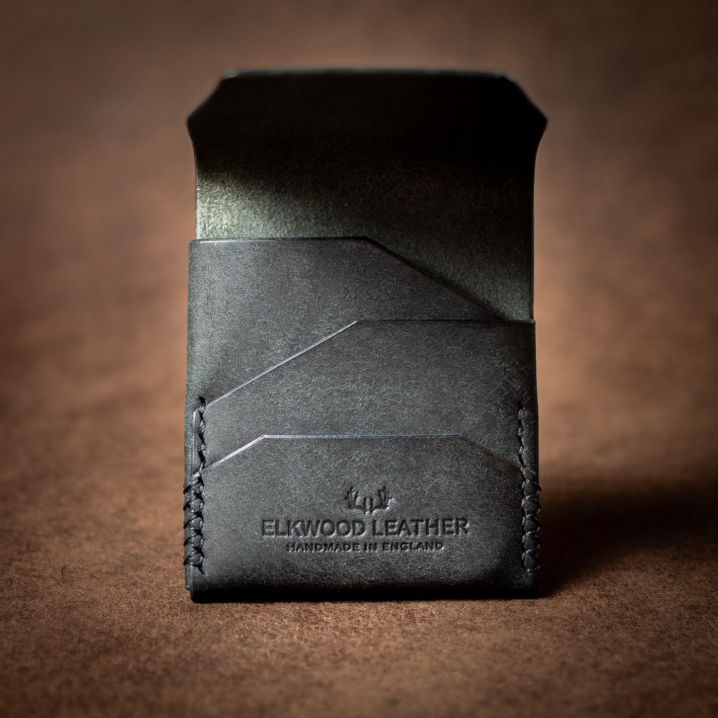 Elkwood Leather black leather EDC wallet with black stitching on a brown leather background open