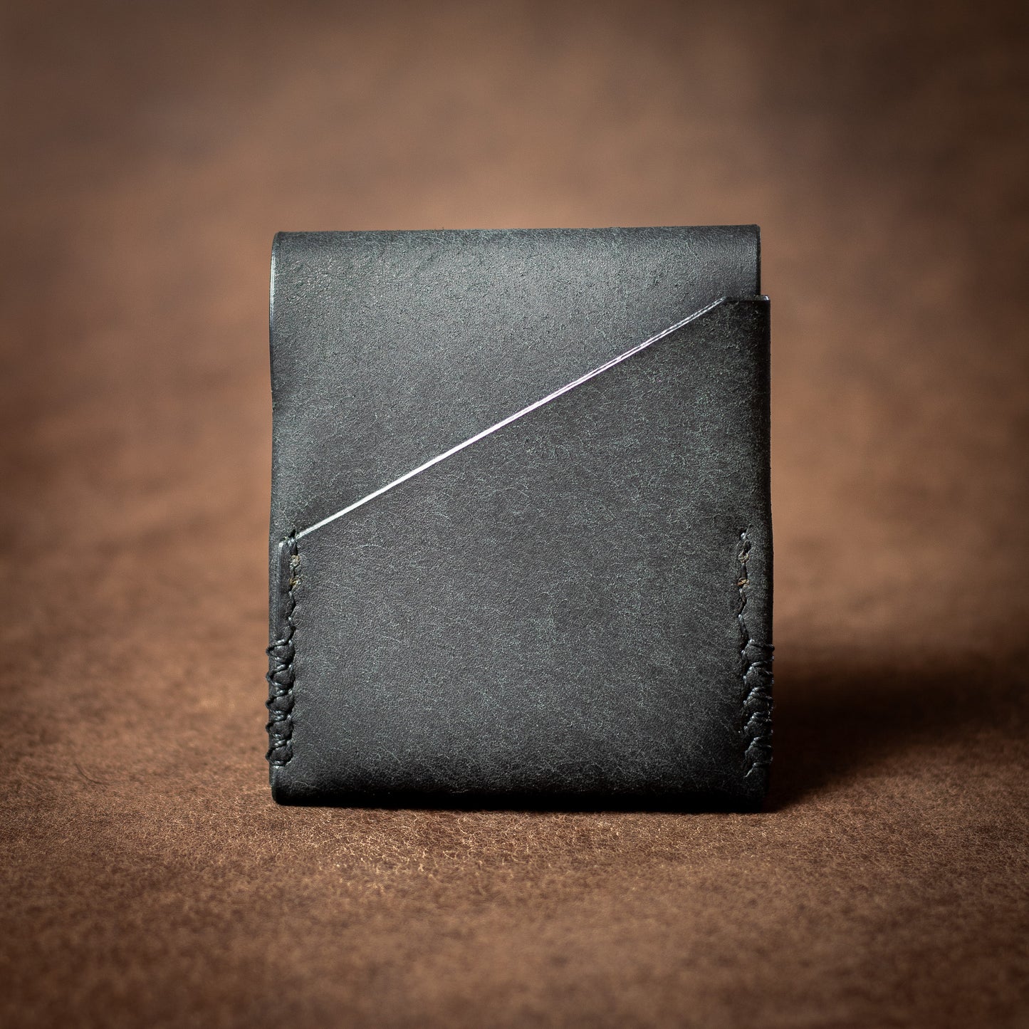 Elkwood Leather black leather EDC wallet with black stitching on a brown leather background reverse quick access slot