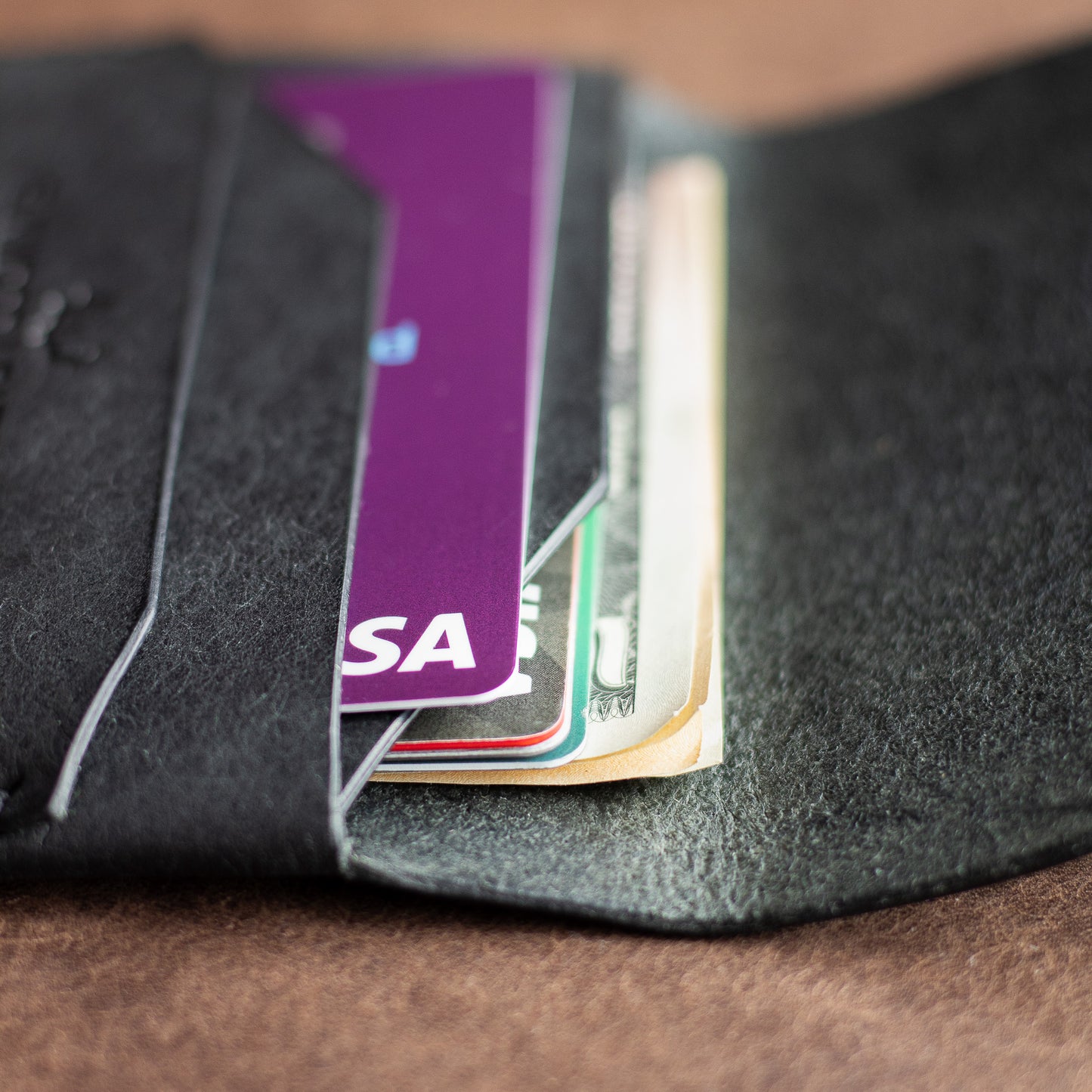 Closeup of credit cards and cash inside a black full grain leather EDC wallet 