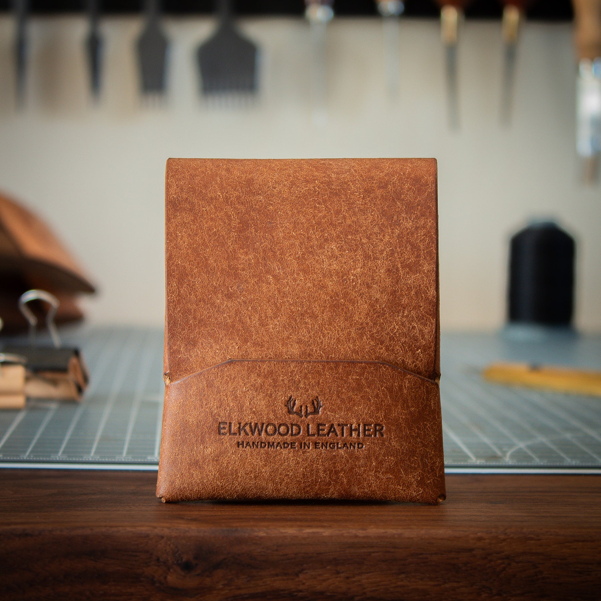 Brown leather switchless wallet with leathercraft tools in the background